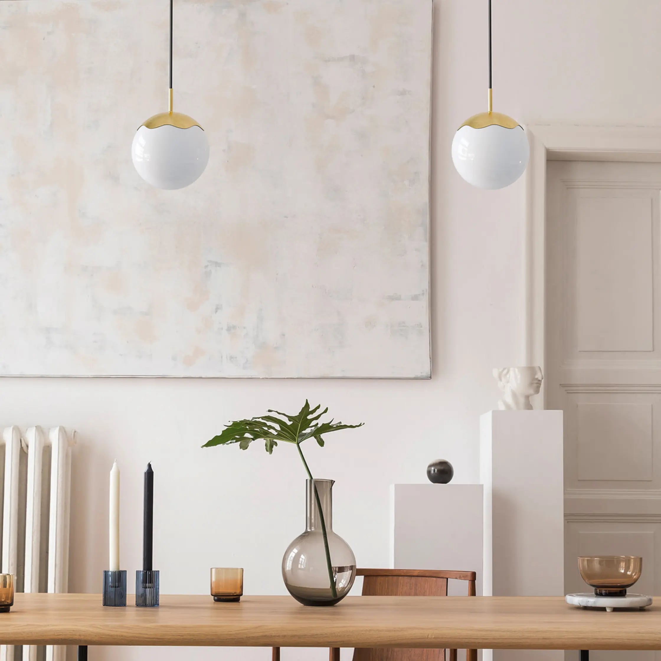 Modern dining room with wooden table, decorative items, and pendant lights.