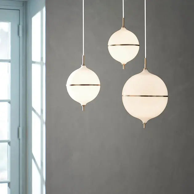 Three spherical pendant lights hanging against a gray wall with a window on the left.