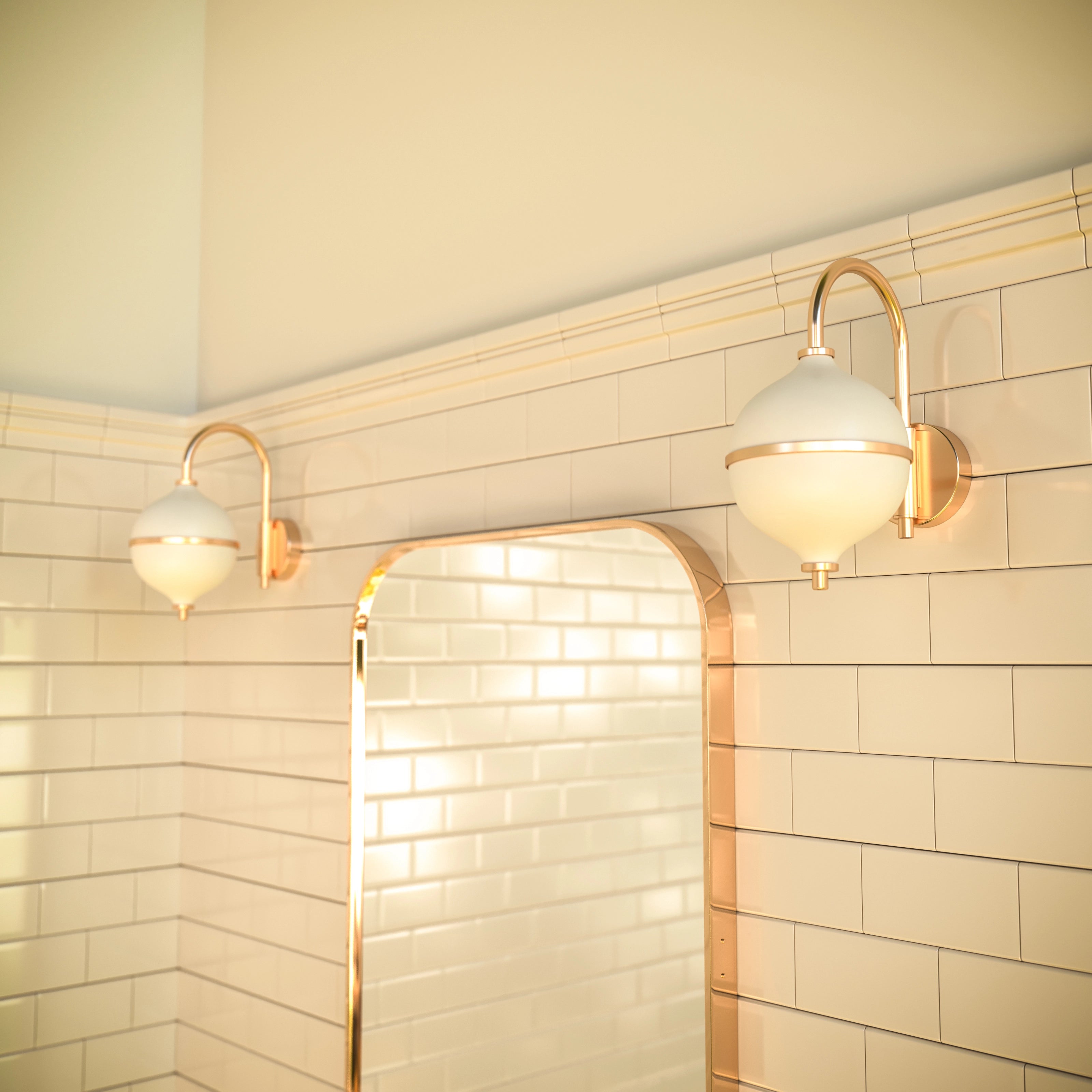 Bathroom with gold-framed mirror and wall lights against tiled walls