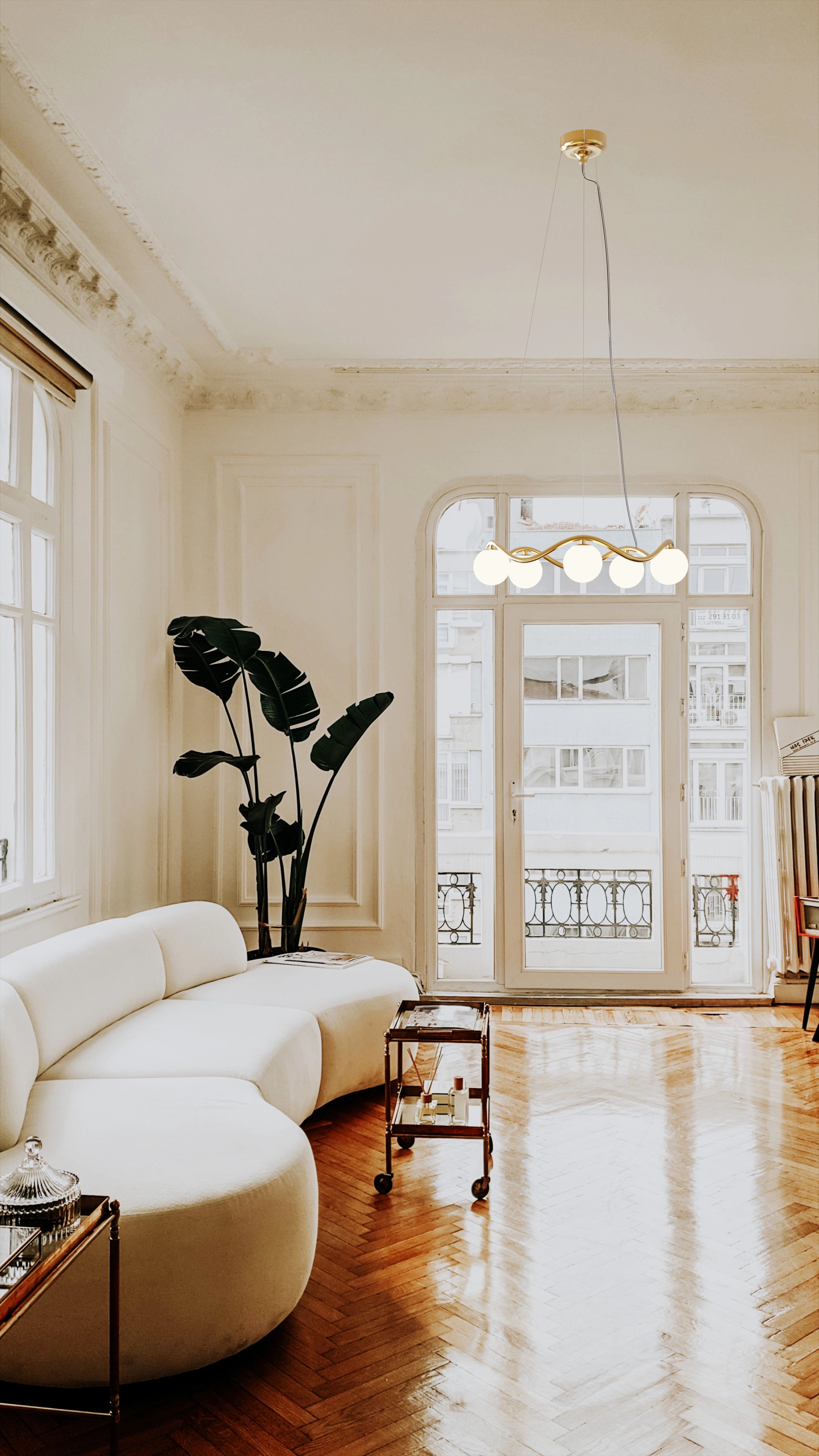 Modern living room with white sofa, large window, and decorative plant.