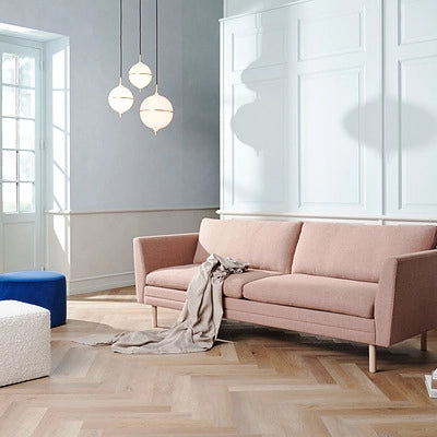 Pink sofa in a modern living room with large windows and pendant lights.