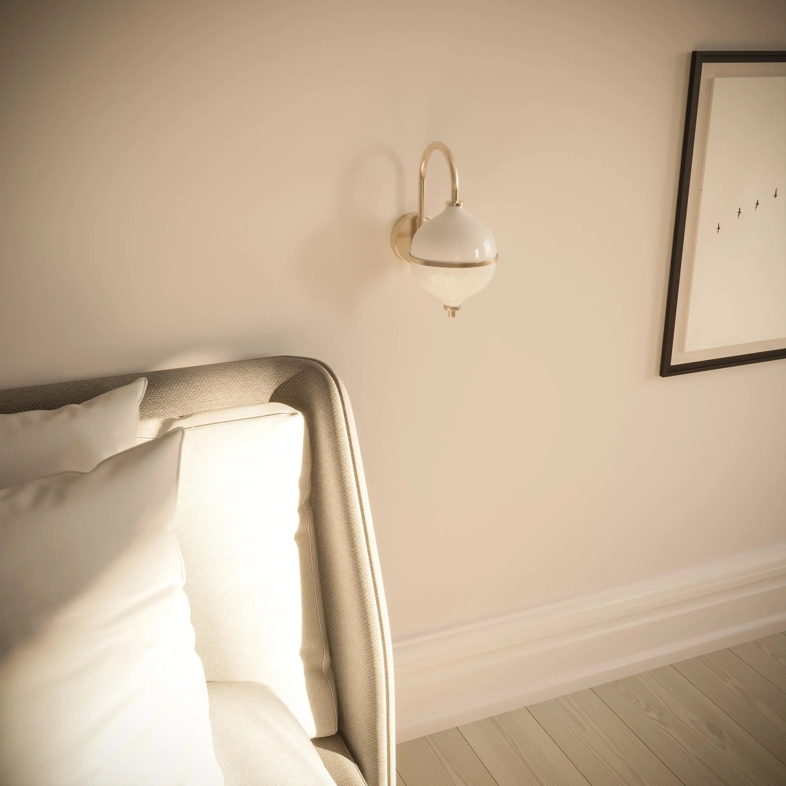 Neatly made bed with pillows in a bedroom setting, featuring a wall sconce and framed picture.